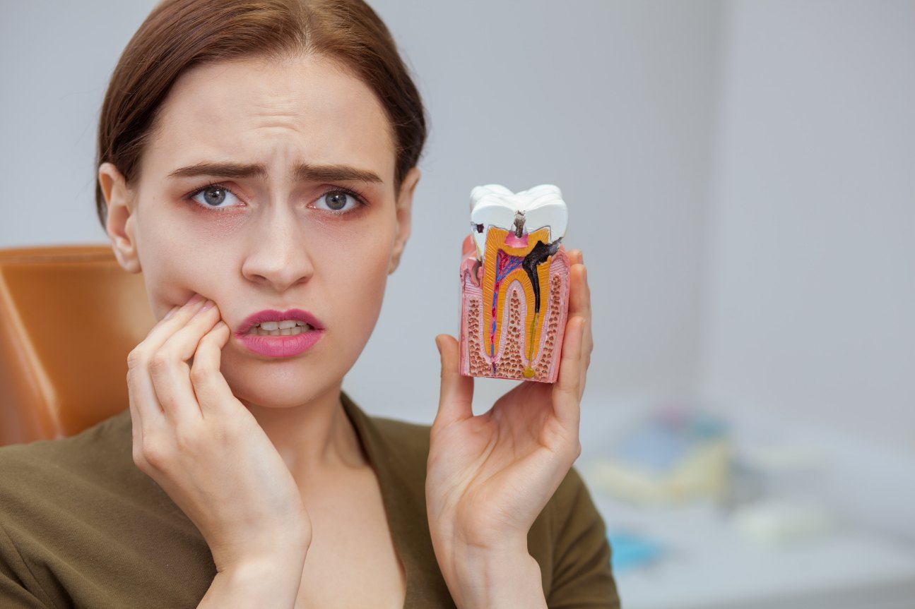Paciente com dor mostrando modelo de dente com cárie